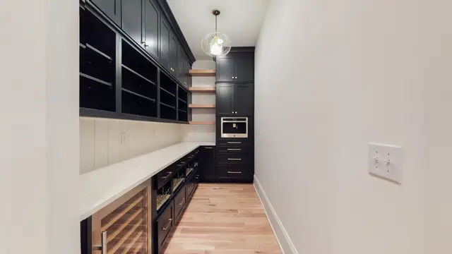Black bar cabinetry with floating shelves and a wine fridge