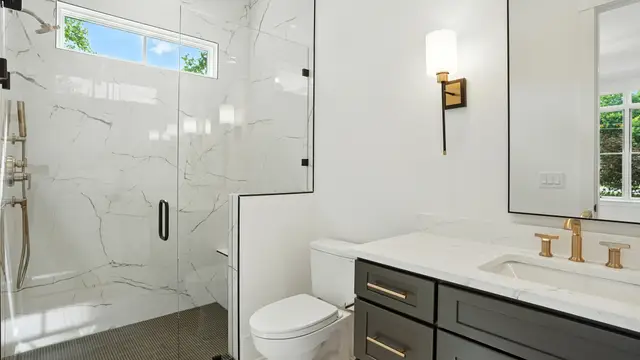 Charcoal vanity beside a marble-tiled shower