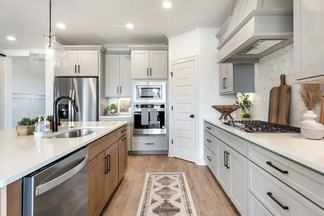 Oyster cabinetry with a Sand island and range wall