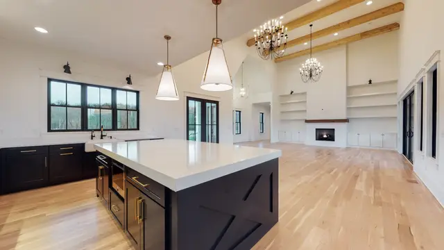 Open-plan kitchen with a Black island and beamed ceiling