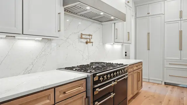 Range wall with a marble slab backsplash over Sand base cabinets
